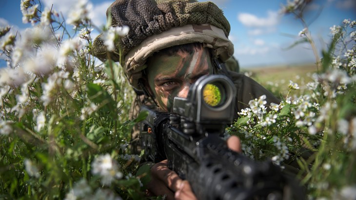 חייל מסתכל בכוונת של הרובה במצב שכיבה בשדה